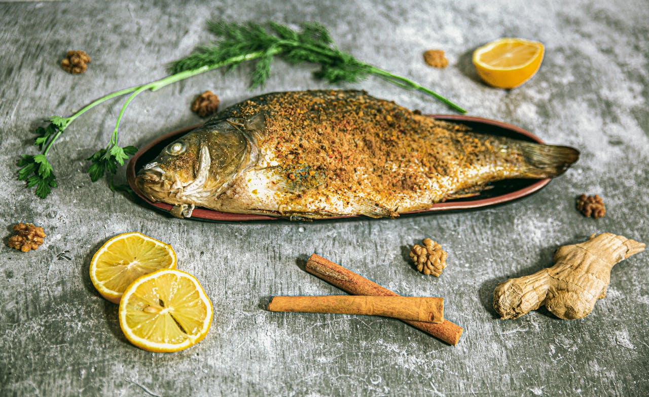 Delicious roasted fish served with spices and fresh herbs on a wooden surface.